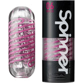 A transparent cylindrical container with a pink spiral design inside, placed next to its black and gray box packaging labeled "TENGA Spinner Penis Stroker | 'Brick' 06." The Tenga box also features a viewing window that showcases this reusable male masturbator.